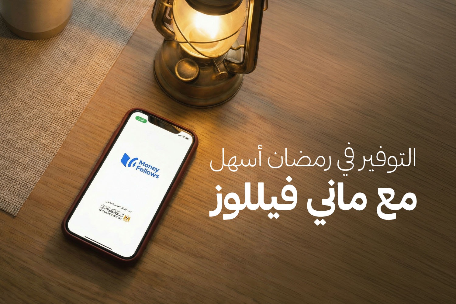 موبايل وعليه لوجو أبلكيشن ماني فيللوز ولوجو البنك المركزي المصري وجنبه فانوس رمضان. الأبلكيشن بالشراكة مع بنك مصر